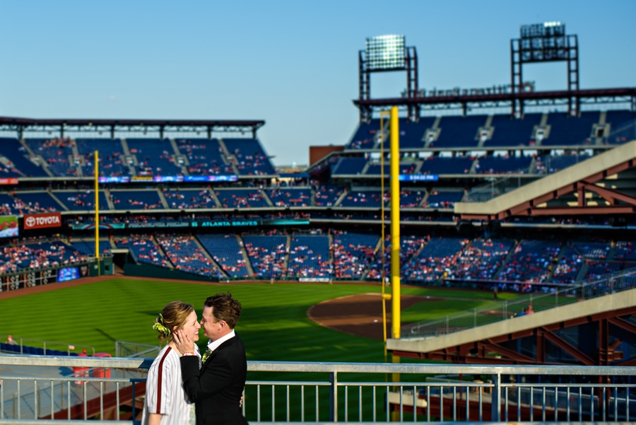 A bride and groom enjoy a kiss at a phillies game on their way to their private box for the reception.